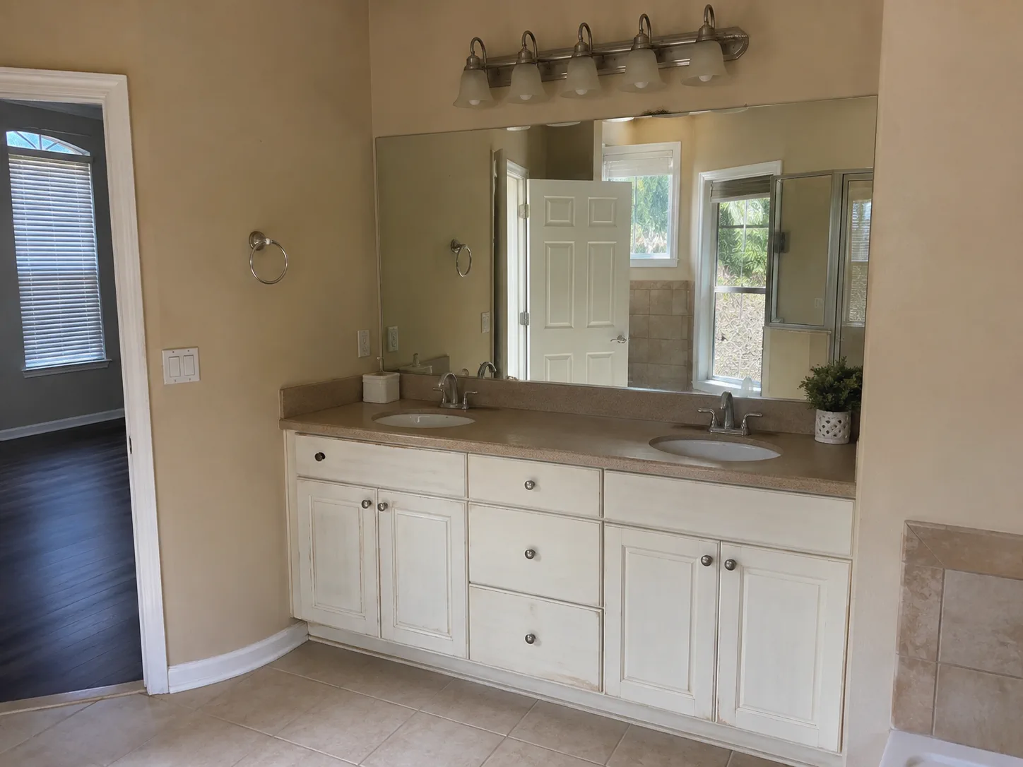 Earlier bathroom with white double vanity and older countertop