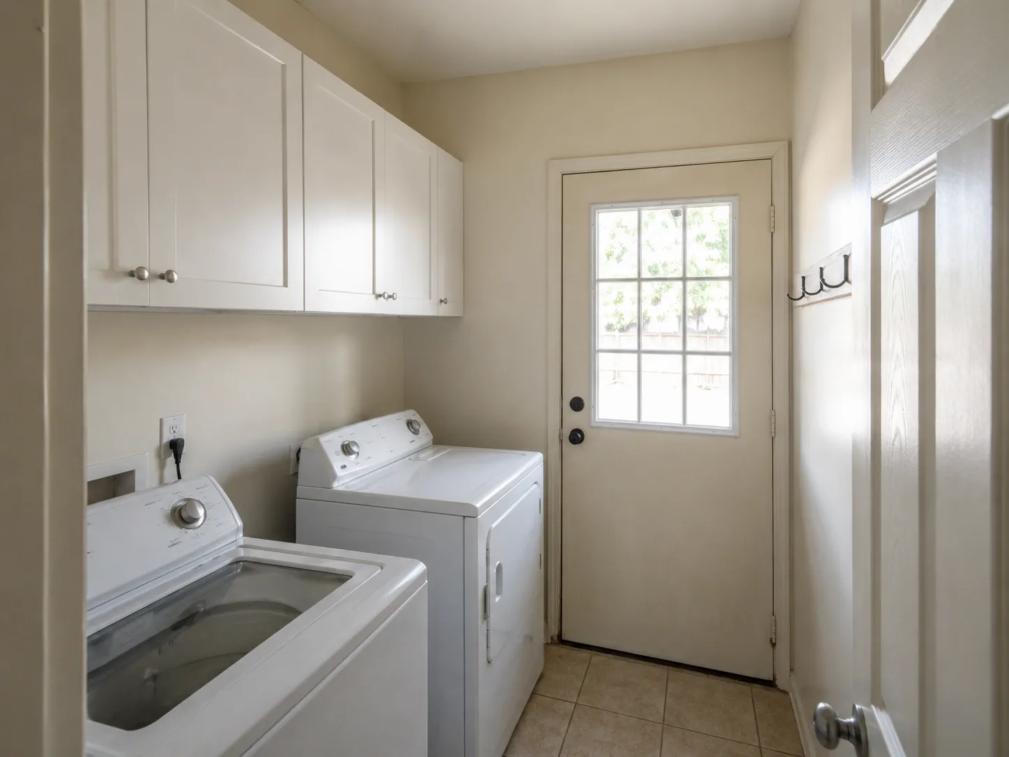 Earlier laundry room with basic white cabinets and exposed appliances